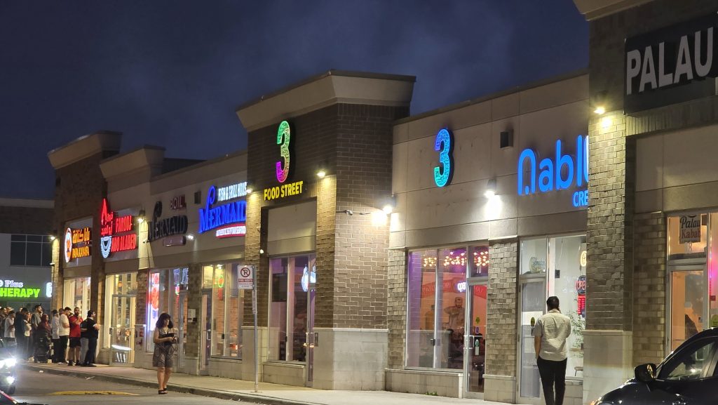 Ridgeway Plaza storefronts illuminated at night