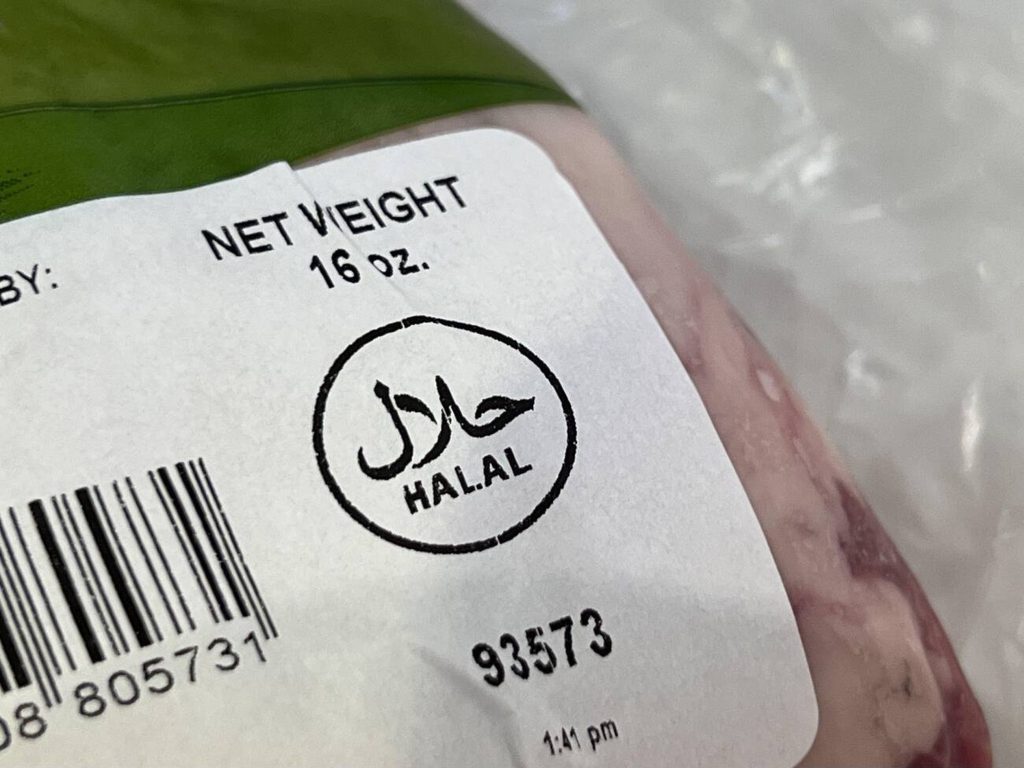 A close-up of a food label on packaged meat, prominently featuring the official Halal certification logo.
