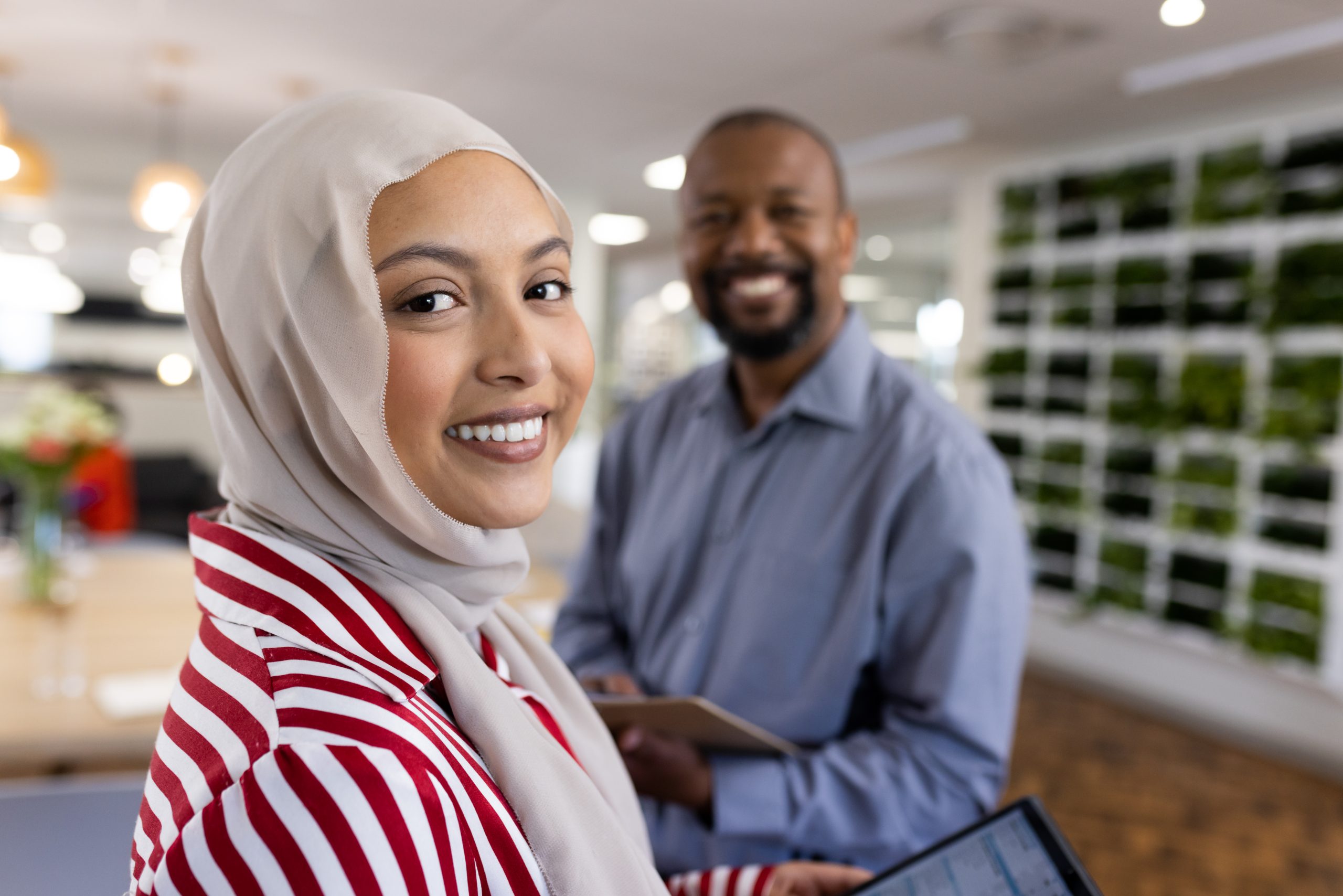 Happy diverse female and male businesspeople looking at camera in office. Business, corporation, working in office and cooperation concept.
