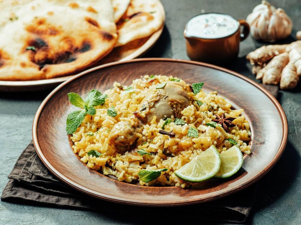 Authentic Pakistani chicken biryani served with naan bread, yogurt sauce, and fresh herbs