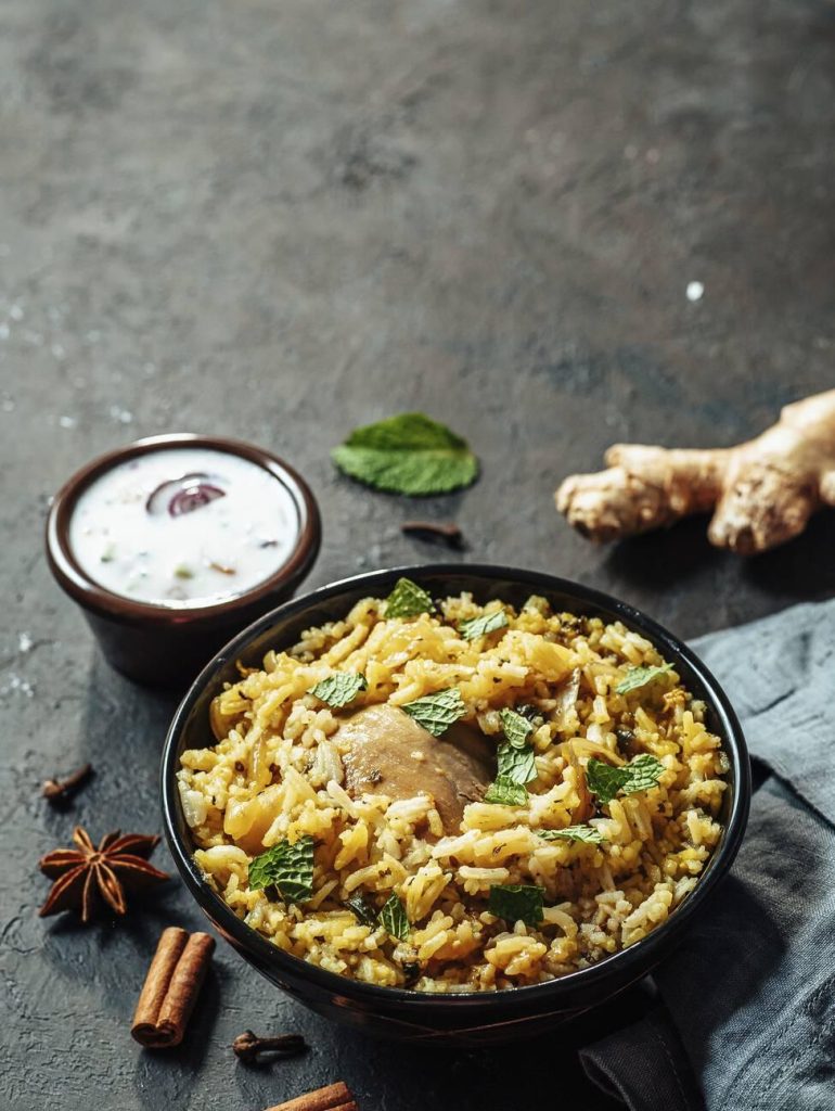 Delicious bowl of Pakistani chicken biryani garnished with fresh mint and served with raita