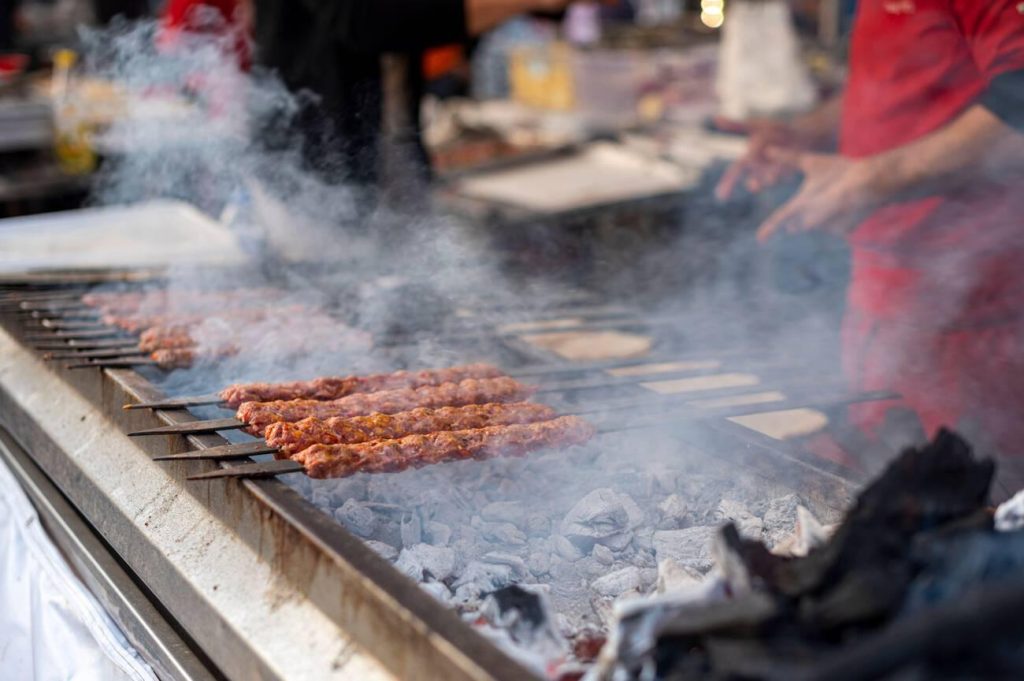 Traditional Adana kebab from Turkish cuisine, served with grilled vegetables and flatbread.