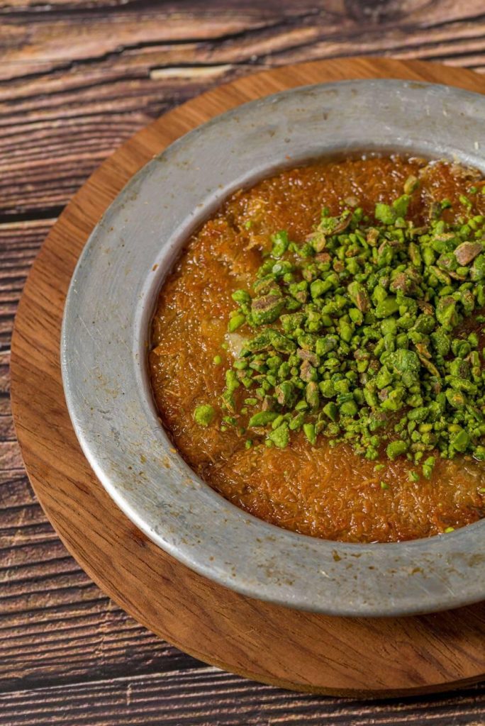 Traditional Syrian dessert pistachio kunefe on wooden table