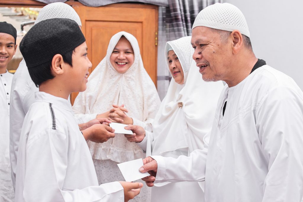 Joyful Muslim children dressed in new clothes holding Eid gifts and smiling.