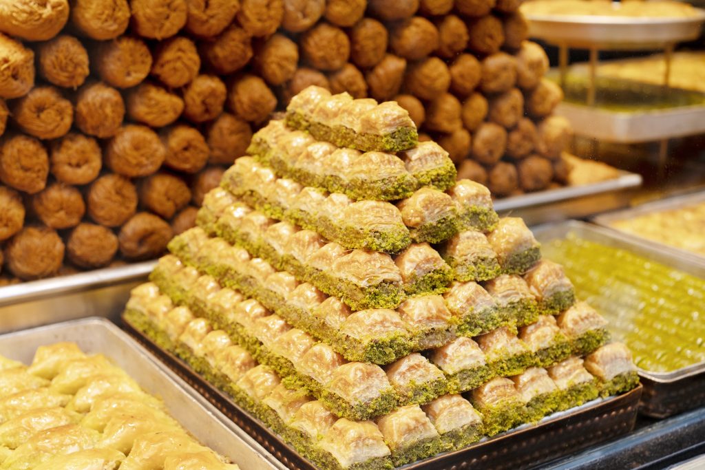 "A pyramid of crispy Turkish Baklava layers filled with pistachios and honey syrup, a famous Eid al-Fitr treat."