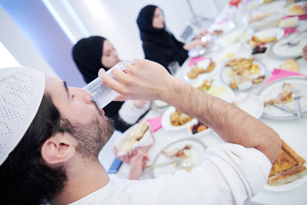 Muslim family having Iftar dinner drinking water to break feast