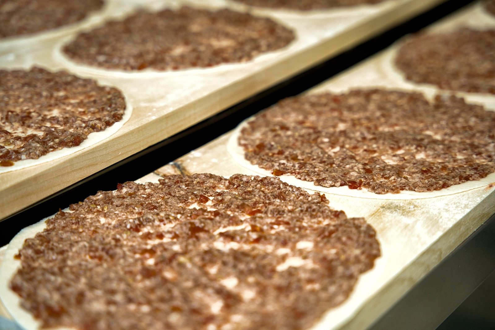 Fresh lahm baajin on a wooden peel at Sahtein Bakery