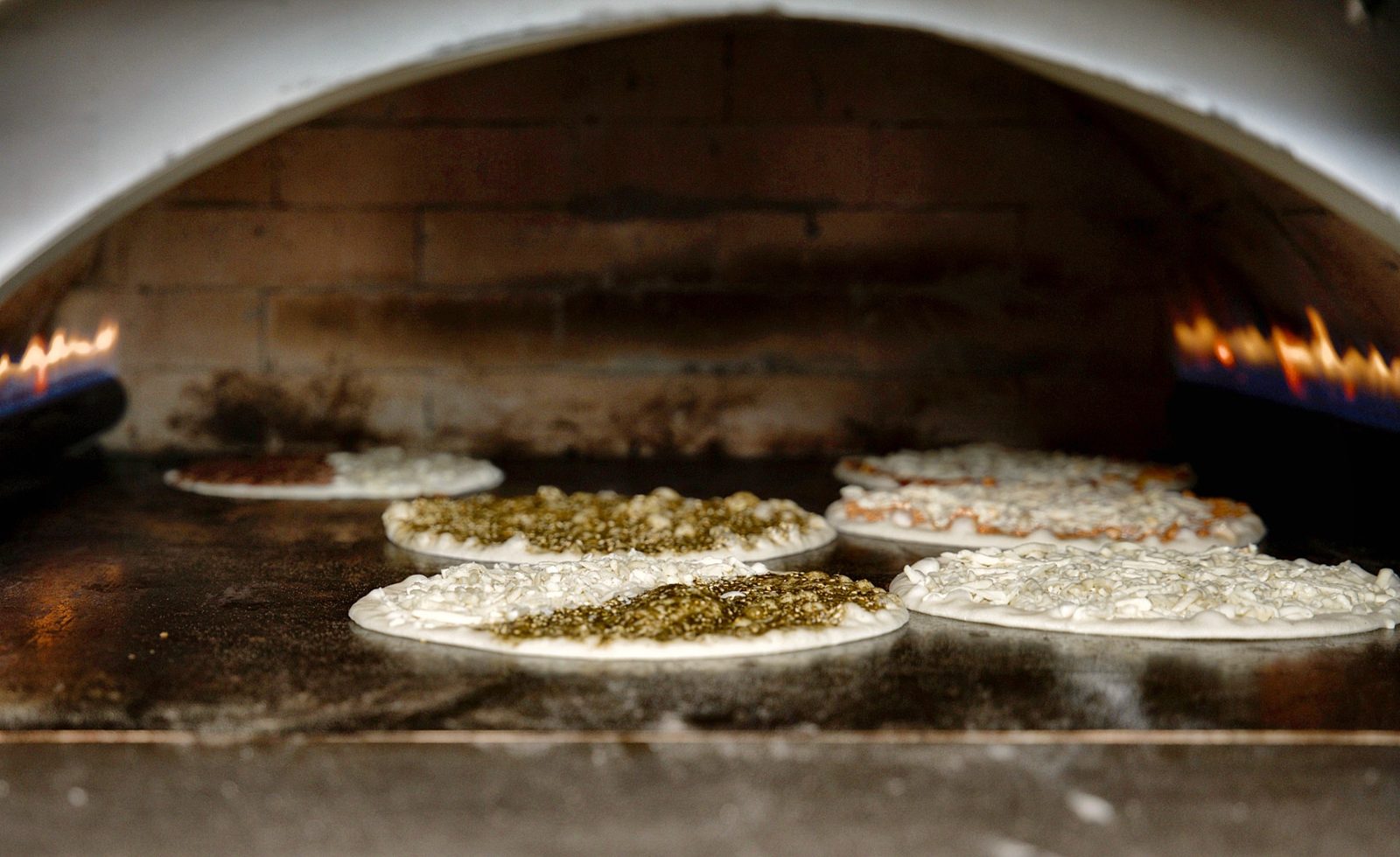 Cheese and zaatar manaeesh baking in Sahtein Bakery stone oven