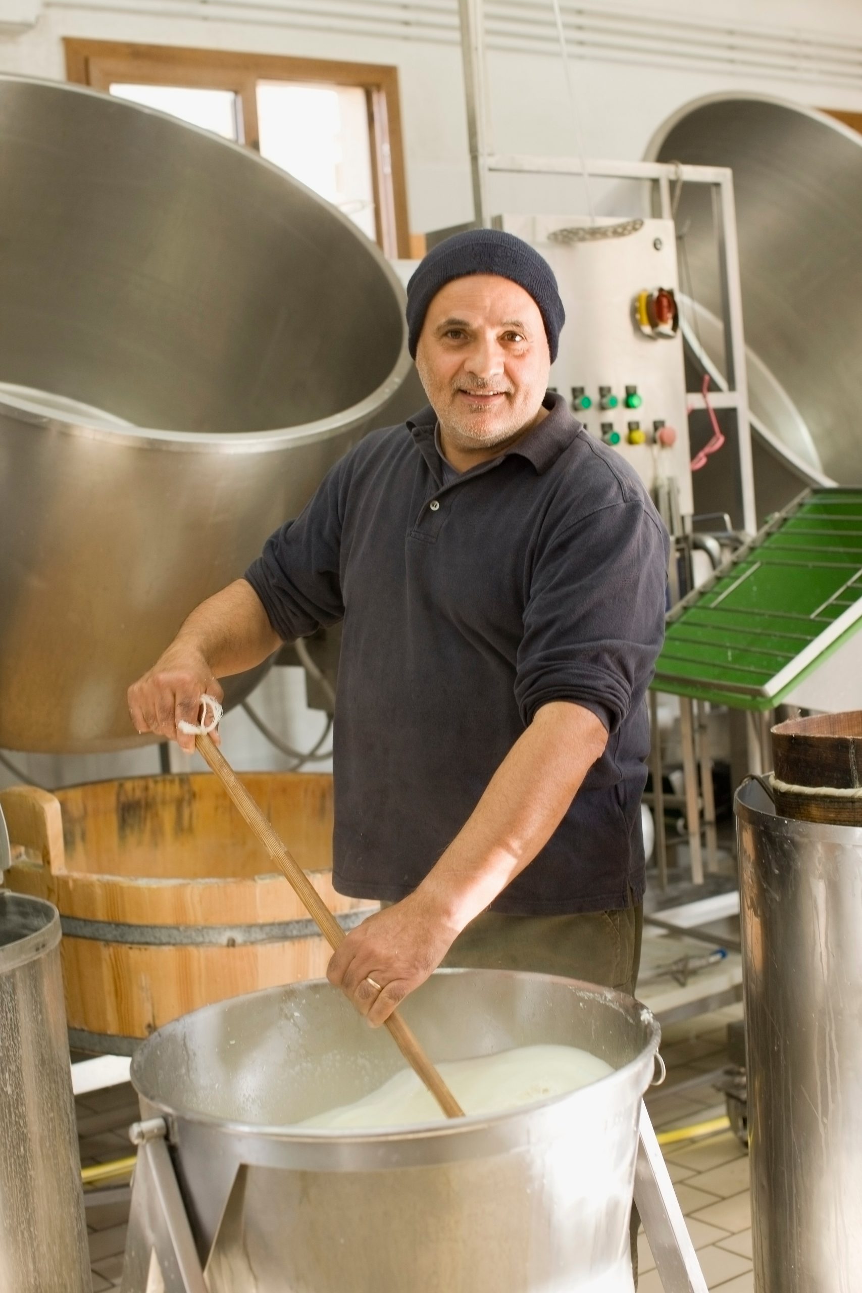 Cheesemaker stirring milk in a large vat