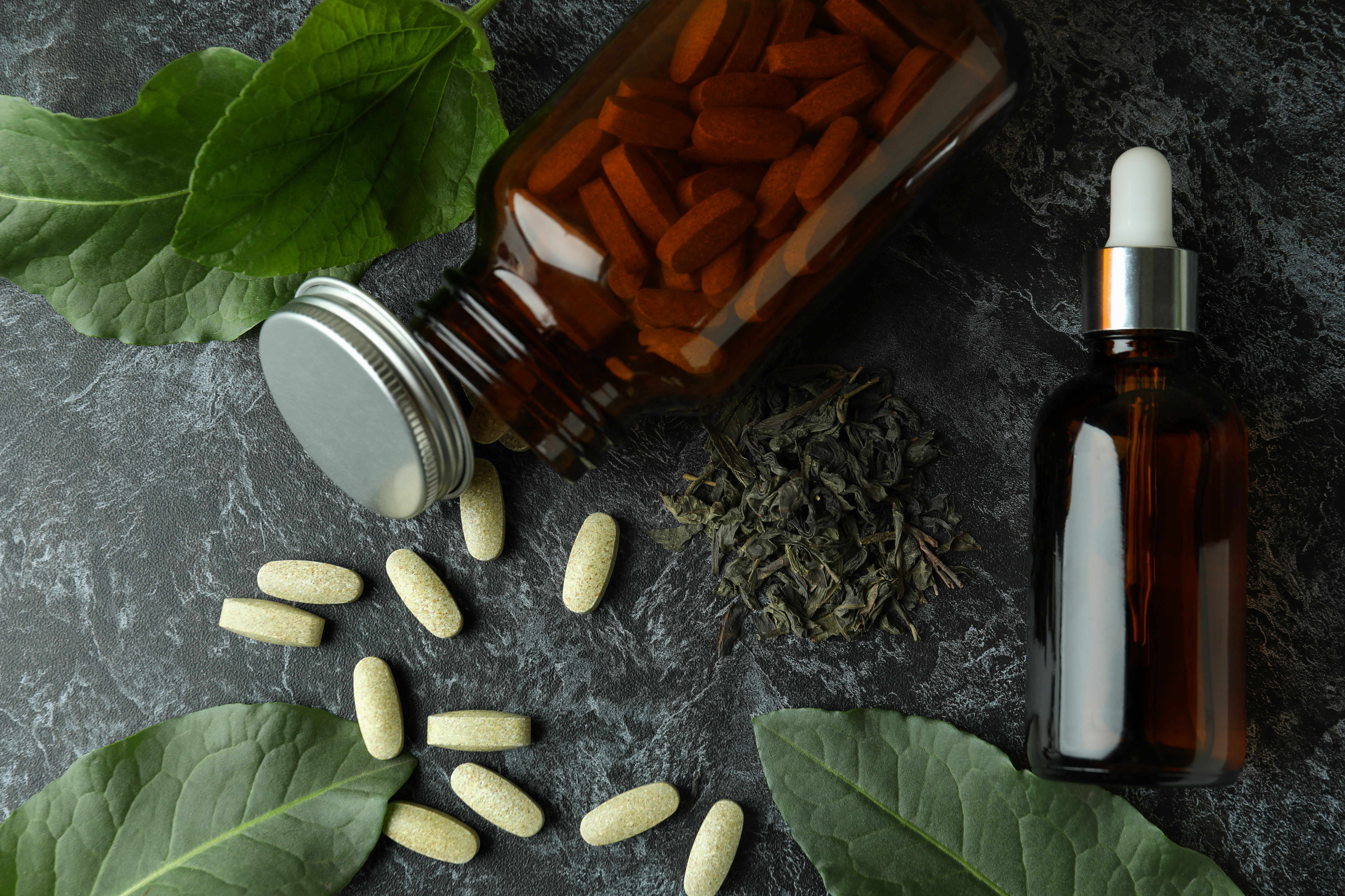 Bottles of vitamins and supplements arranged with green leaves