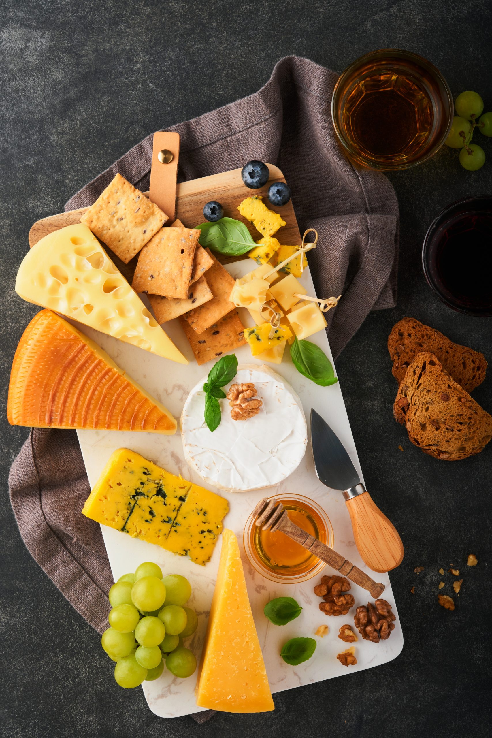 Cheese board with crackers, fruit and wine glasses