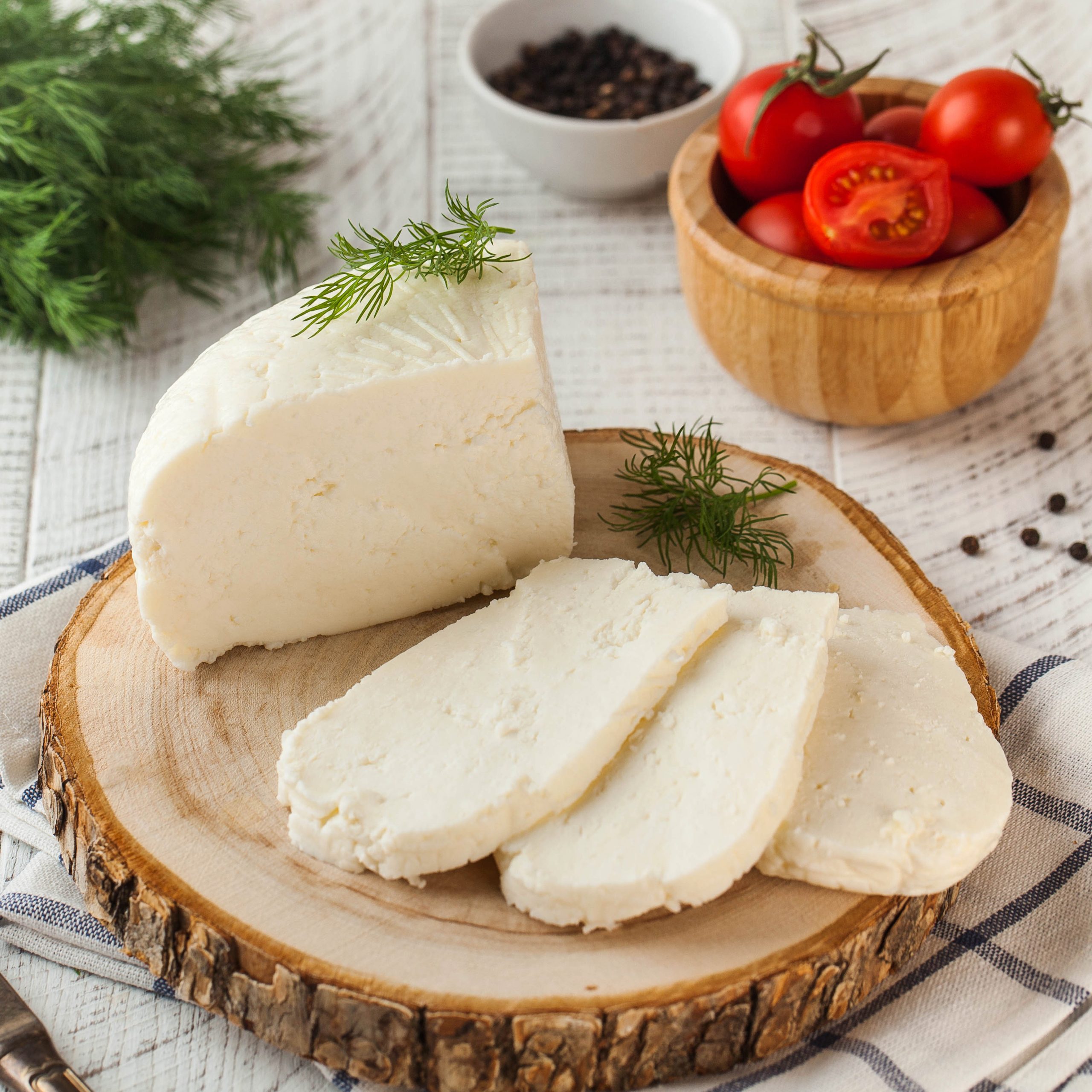 White cheese with cherry tomatoes and dill on a wooden board
